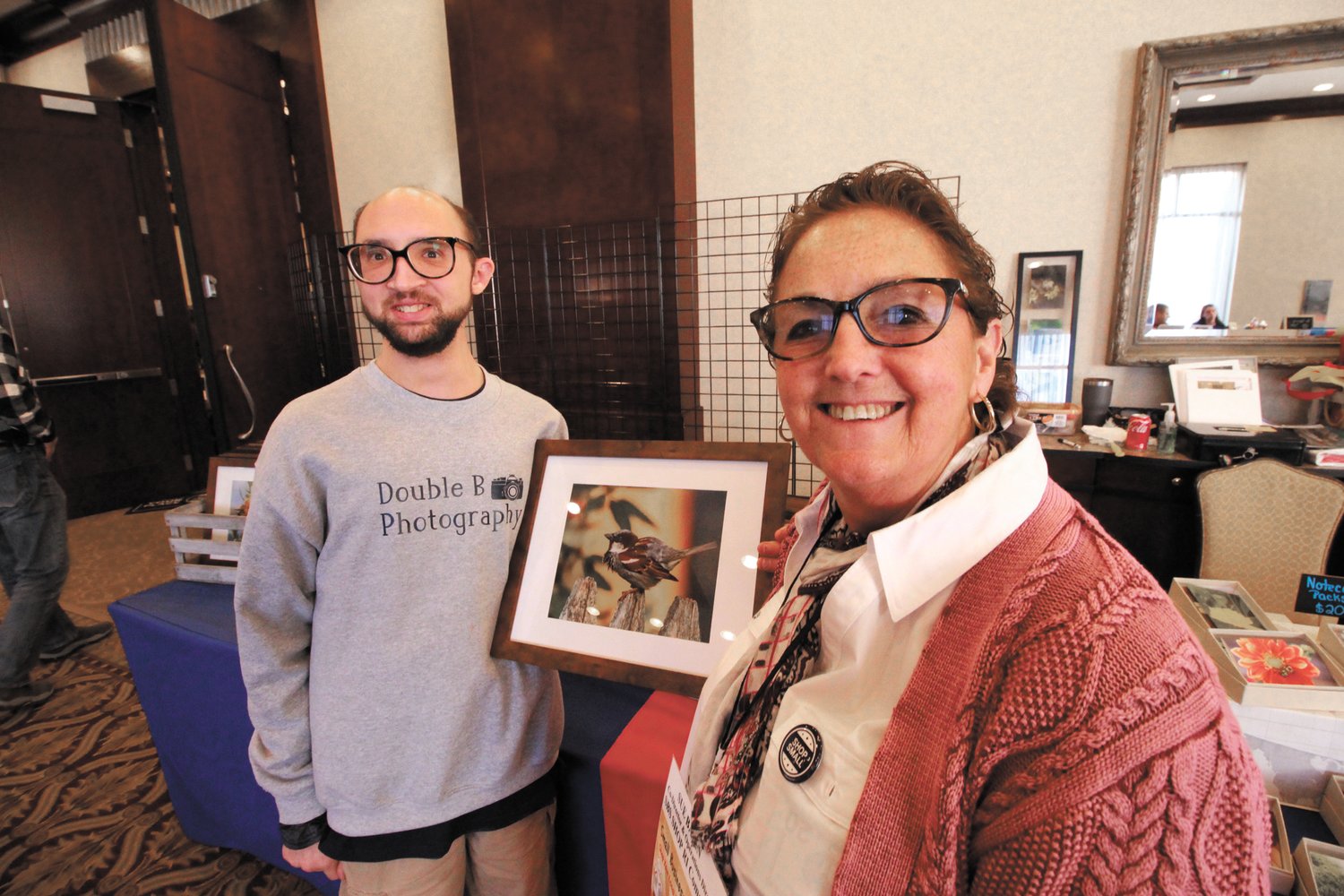 BIRDS ARE HIS FAVORITE:  Bryan Baron, owner of Double B Photography, one of 32 entrepreneurs with disabilities at Small Business Saturday shows off one of his works to Sue Babin, co-chair of the event hosted by the Rhode Island Disabilities Council.